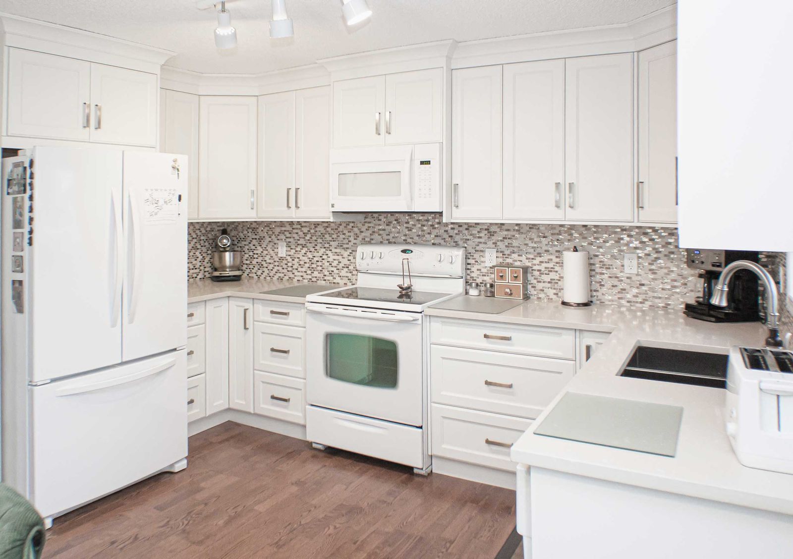 A bright, white kitchen with custom cabinets and matching white appliances, showcasing the seamless look often achieved when comparing supply-only cabinets vs full-service kitchen remodeling.