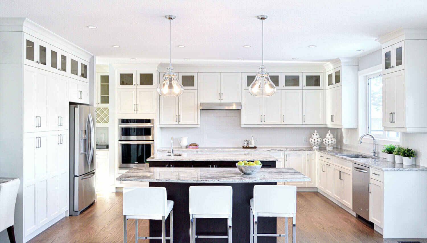Contemporary kitchen with dark built-in cabinetry, stainless steel appliances, and a large island, demonstrating how built-in storage improves function and longevity through organized, space-saving design.