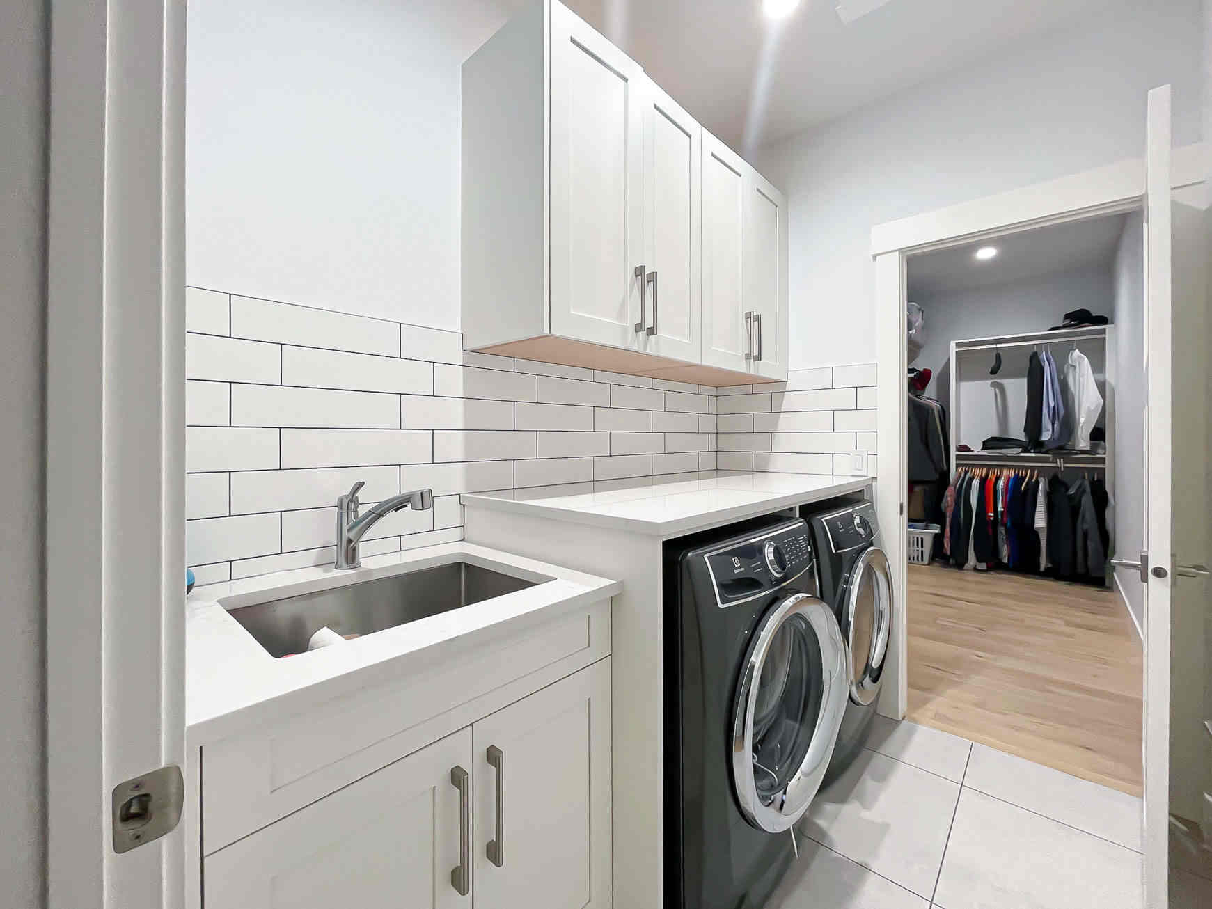 Modern white laundry room with upper cabinets, countertop workspace, and front-load washer and dryer, designed to organize laundry room cabinets and keep supplies neatly stored.