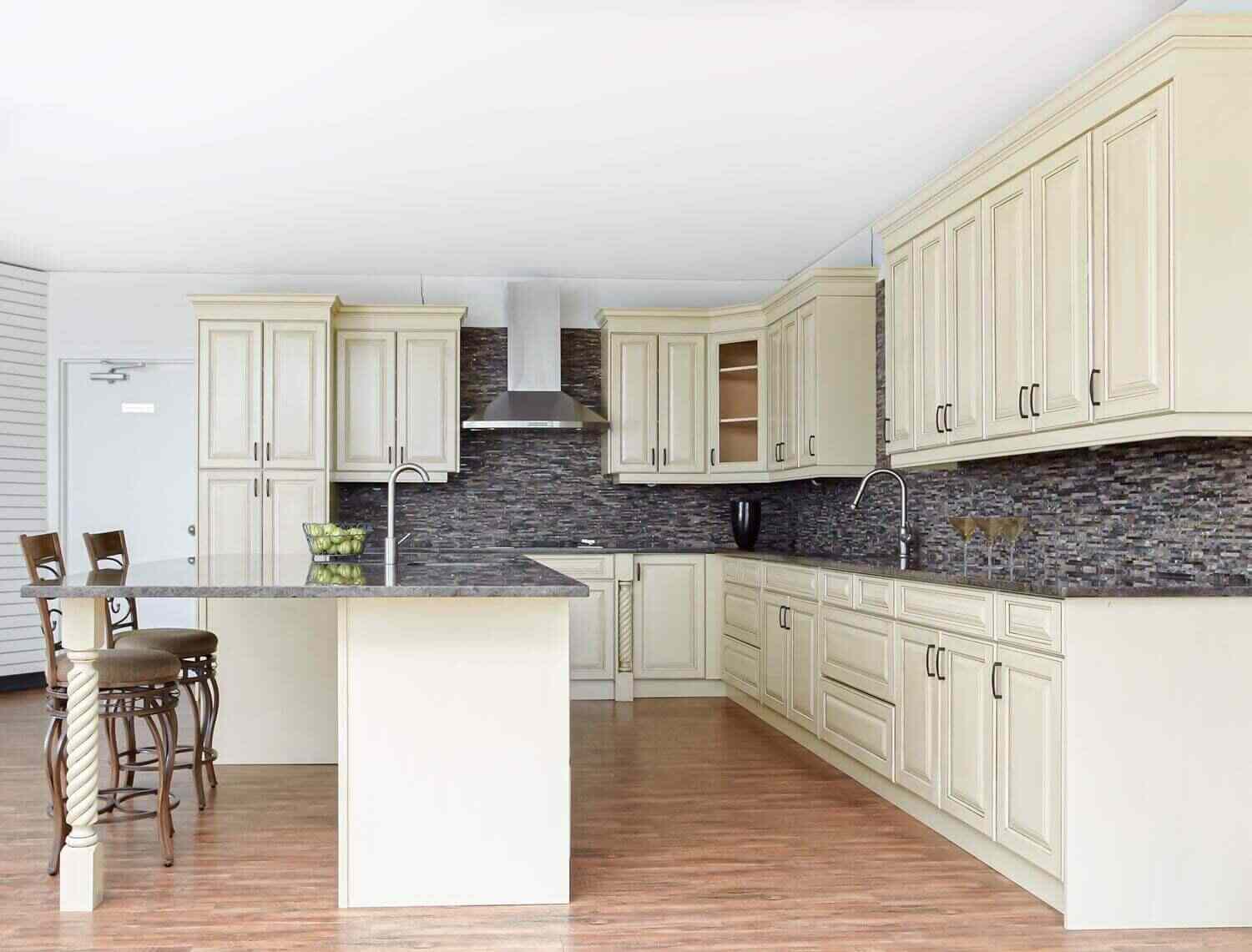 Spacious kitchen with newly installed cream cabinetry, large island, and updated backsplash, illustrating why replacing cabinets is the better choice for a fresh, modern upgrade.