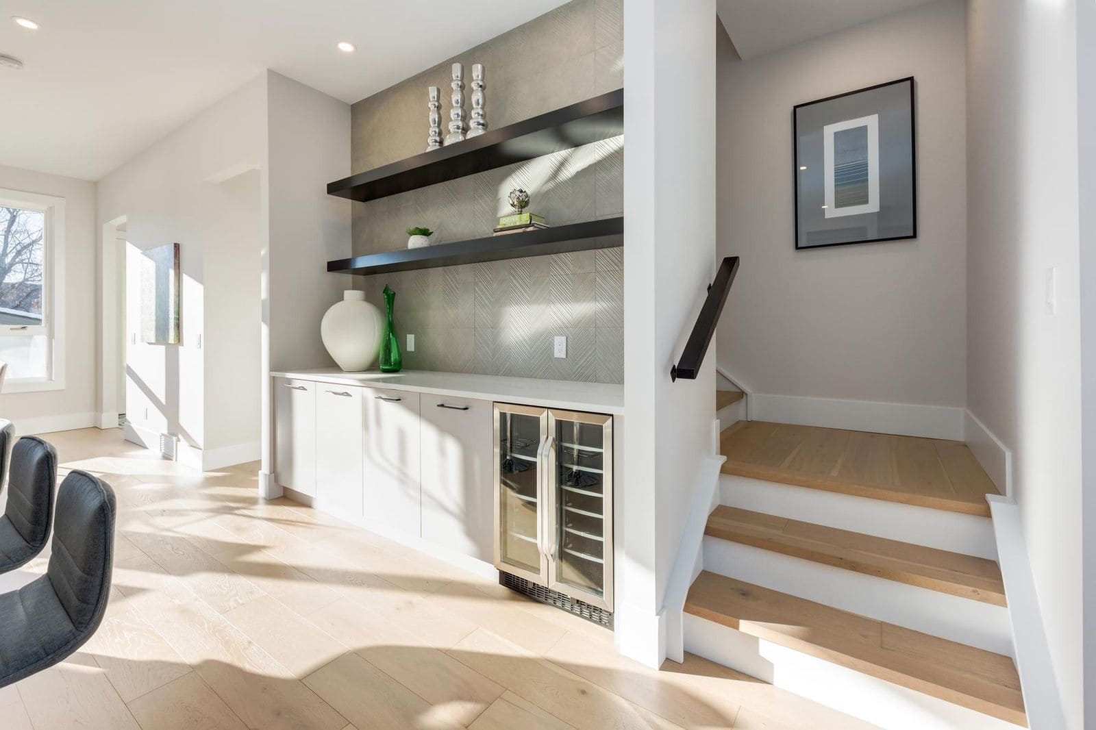 Compact wet bar design that maximizes space with built-in cabinetry, open shelving, and under-counter beverage fridge in a modern home interior.