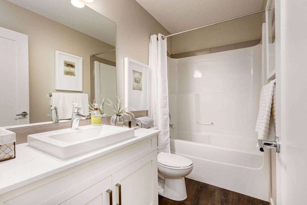 Bathroom showcasing material selection and finish quality with white vanity, modern fixtures, bathtub with shower curtain, and neutral wall tones.